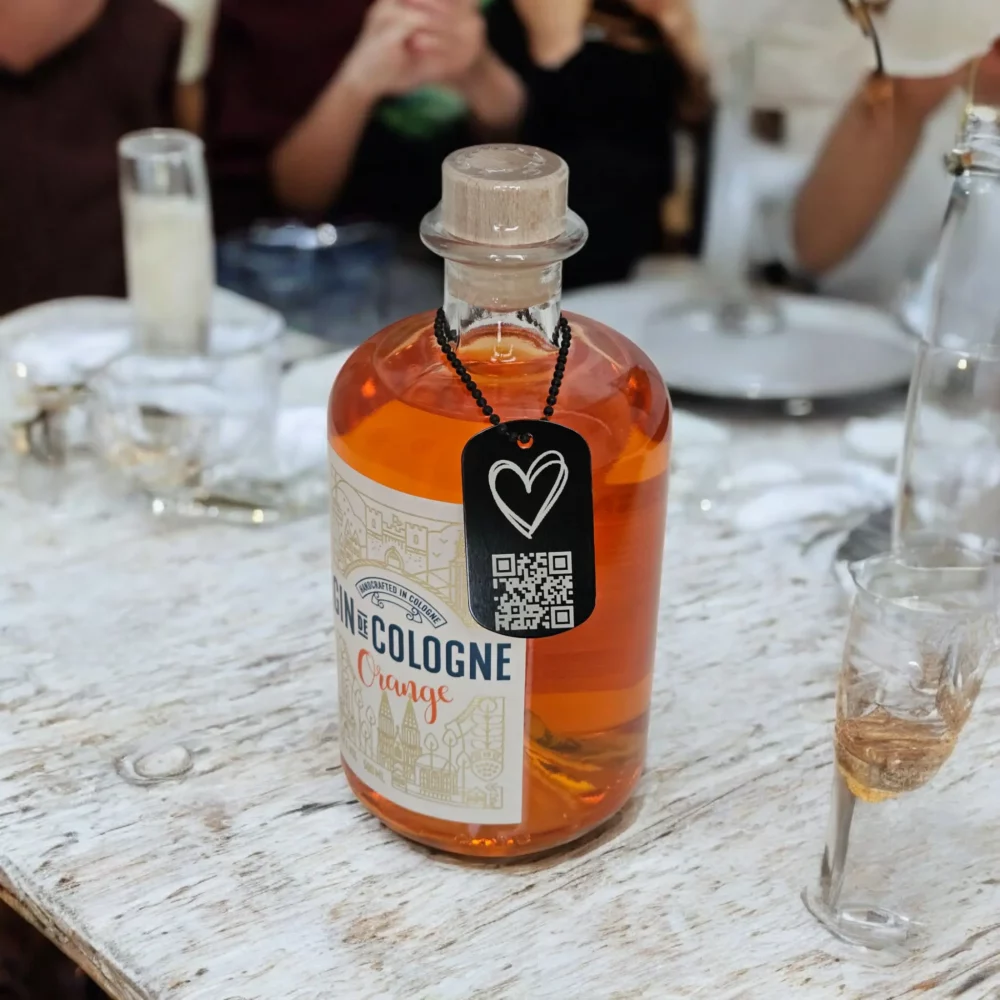 Der Heart-Anhänger von MONVOU wird stilvoll an einer Flasche präsentiert – ideal für persönliche digitale Botschaften mit QR-Code.
