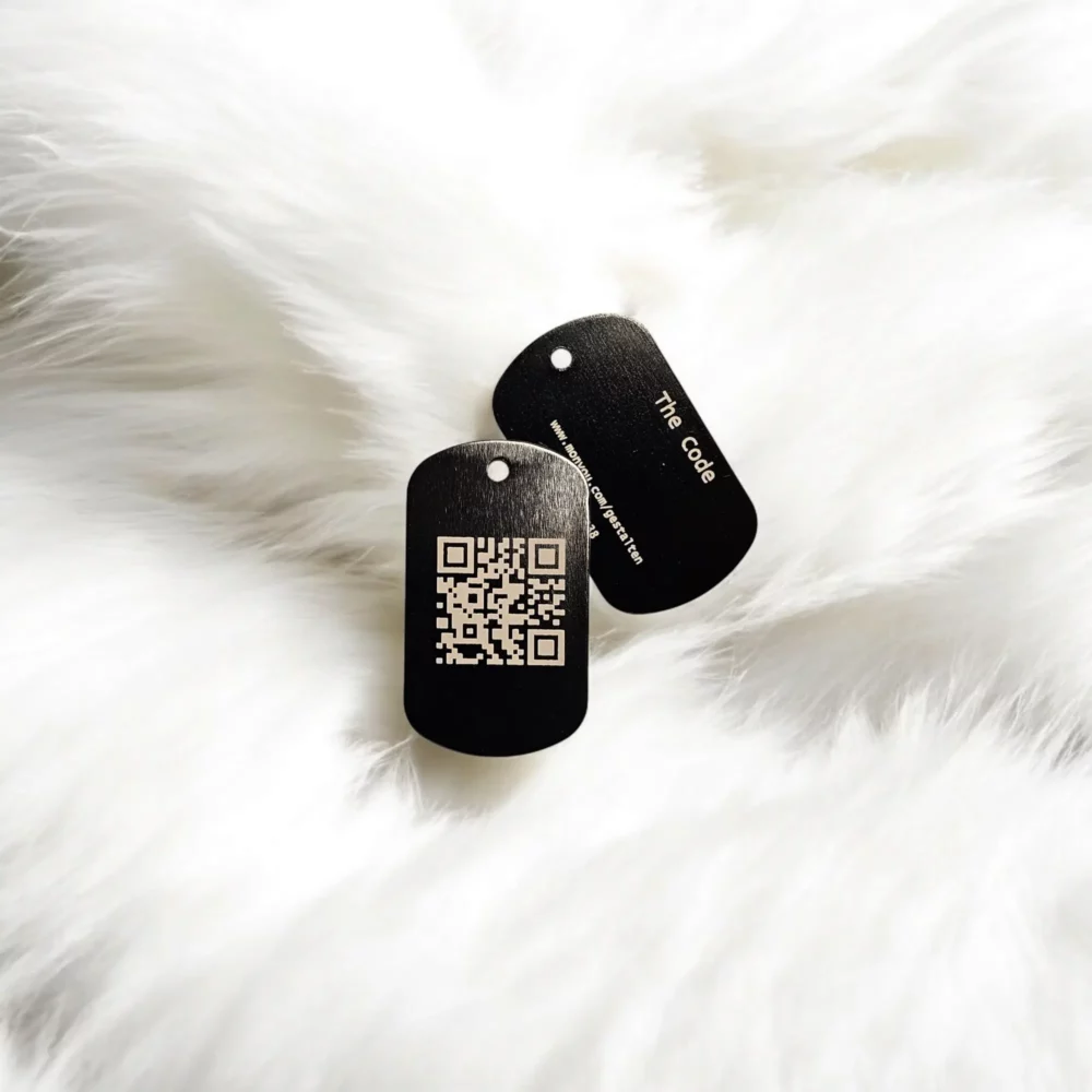 Der Anhänger The Code: Vorderseite mit QR-Code, Rückseite mit graviertem Namen The Code und individueller ID.