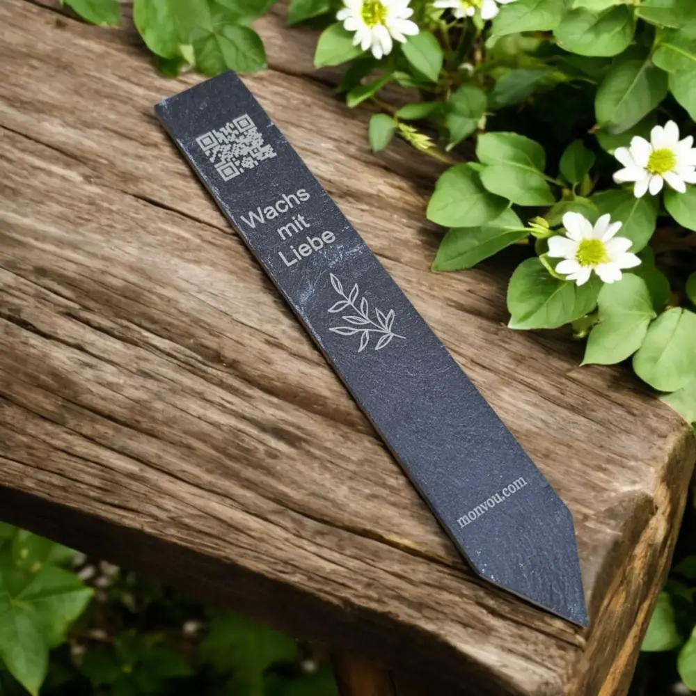 Schiefer Blumenstick graviert mit Spruch und QR-Code auf Holztisch – digitales Geschenk mit persönlicher Botschaft.