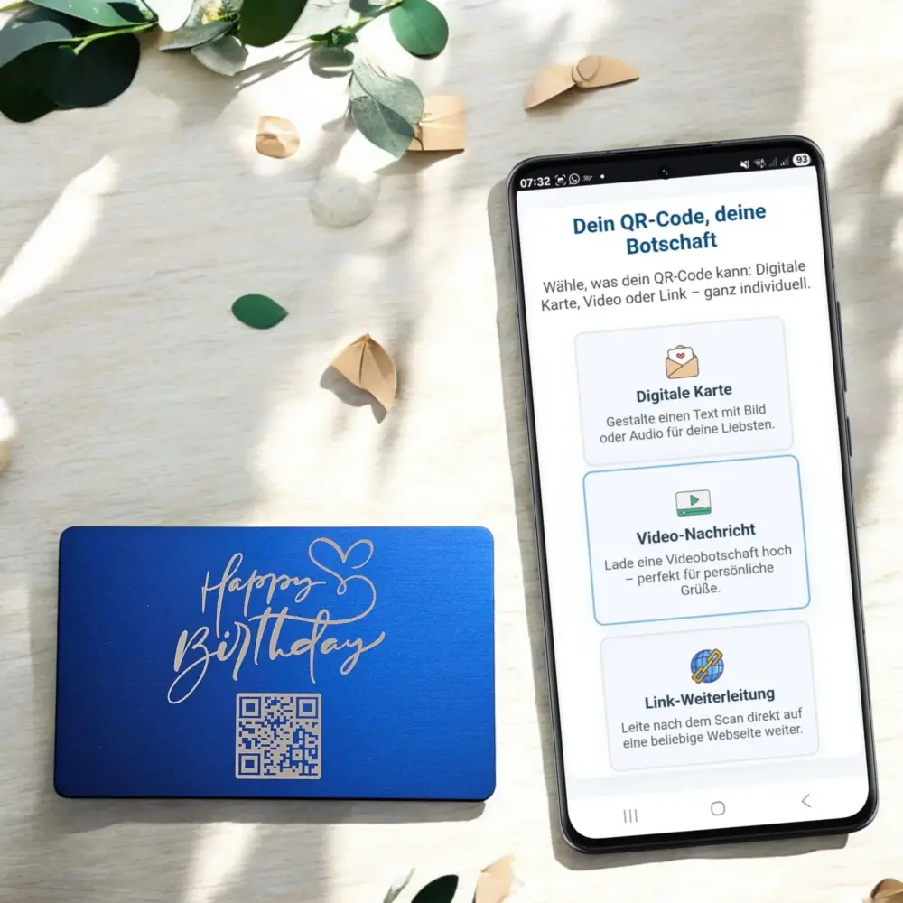 Blaue Metallkarte mit „Happy Birthday“-Gravur und QR-Code neben Smartphone, das die digitale Gestaltung per QR-Code zeigt – ideales personalisiertes Geburtstagsgeschenk mit Video oder Text.