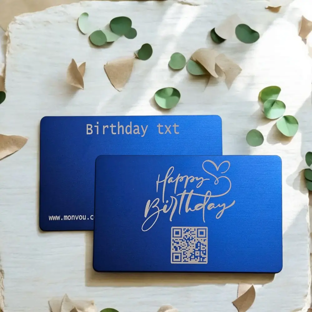 Zwei blaue Monvou-Metallkarten als Geburtstagskarten-Set: Vorderseite mit „Happy Birthday“-Gravur und QR-Code, Rückseite mit Gravur „monvou.com"