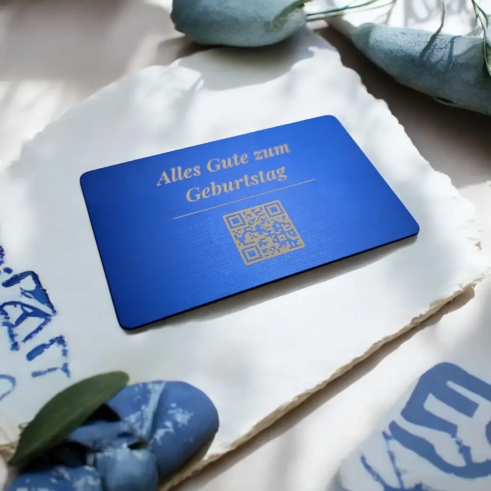 Blaue Metallkarte mit individueller Gravur und QR-Code auf elegantem Hintergrund