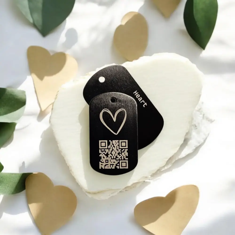 Schwarzer Tag-Anhänger mit Herzgravur und QR-Code auf weißer Steinplatte – personalisierbar