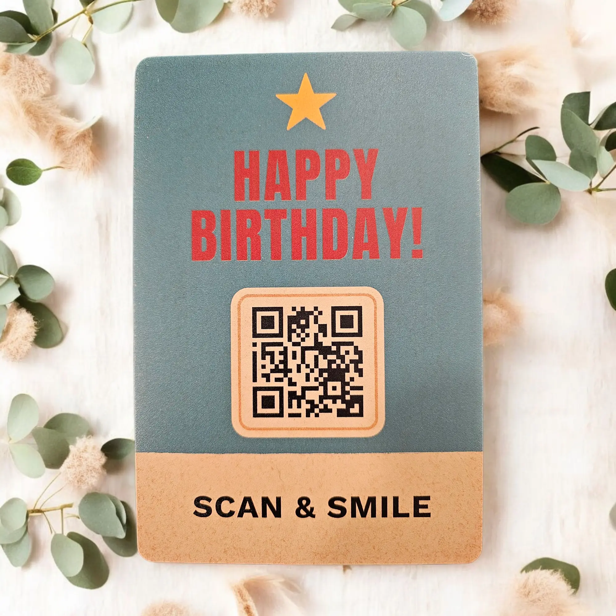Retro Geburtstagskarte aus Metall mit roter „Happy Birthday“-Aufschrift, Stern und QR-Code, umgeben von grünen Blättern – individuell gestaltbar und digital